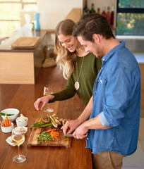 Making the perfect meal together. Shot of a smiling young couple standing at their kitchen counter chopping up ingredients together for dinner.