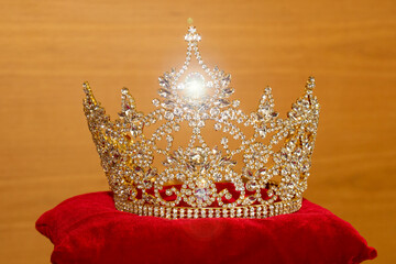 A beautiful golden crown on a red velvet pillow.
