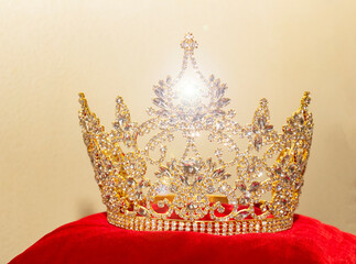 A beautiful golden crown on a red velvet pillow.