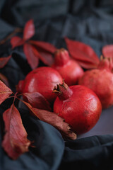 Ripe pomegranates garnished with red grape leaves on a dark background 