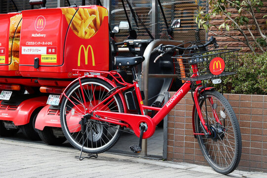 TOKYO, JAPAN - March 17, 2022: A McDonalds delivery electric bicycle parked by a delivery scooter at a McDonalds restaurant in Tokyo's Koto Ward.