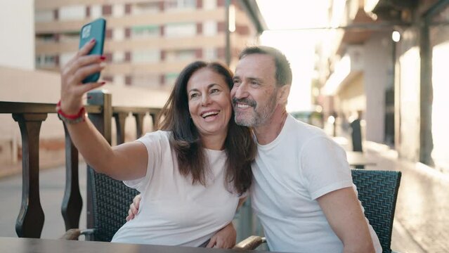 Man and woman couple make selfie by the smartphone sitting on table at coffee shop terrace