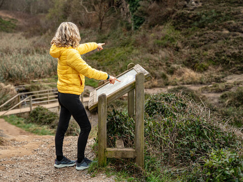 A woman checks an information panel and points the way. Tourist information on an information panel