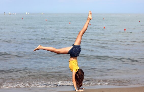 slender girl barefoot on the seashore while effect the rhythmic gymnastics exercises