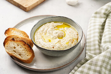 Traditional dish of arabic cuisine baba ganoush made of roasted eggplant, tahin, cilantro, garlic, olive oil, lemon juice with toasted baguette croutons on grey background