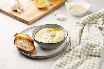 Traditional dish of arabic cuisine baba ganoush made of roasted eggplant, tahin, cilantro, garlic, olive oil, lemon juice with toasted baguette croutons on grey background