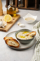 Traditional dish of arabic cuisine baba ganoush made of roasted eggplant, tahin, cilantro, garlic, olive oil, lemon juice with toasted baguette croutons on grey background
