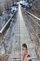 leg of man that walks on the very long  suspension bridge in stainless stee