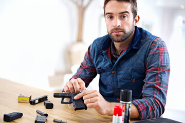 Regular maintenance is essential for every gun owner. A young man cleaning his gun.