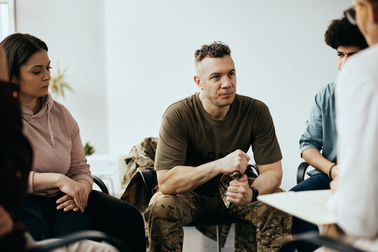 Military Officer Listens To Therapist During Group Therapy Meeting At Community Center.