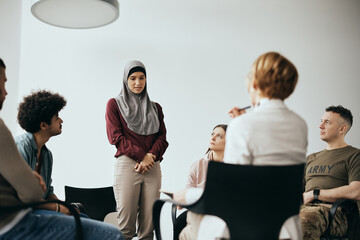 Young Muslim woman talks about her issues during group therapy meeting at mental health center.