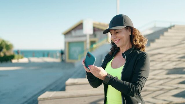 Middle age woman wearing sportswear making selfie by the smartphone at street