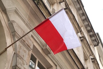 The flag of Poland is developing on the old building of the city.