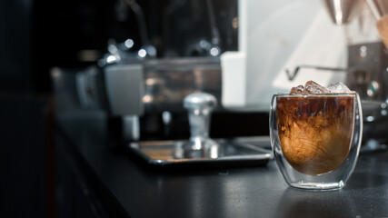 Ice coffee on a black table with cream being poured into it showing the texture and refreshing look of the drink