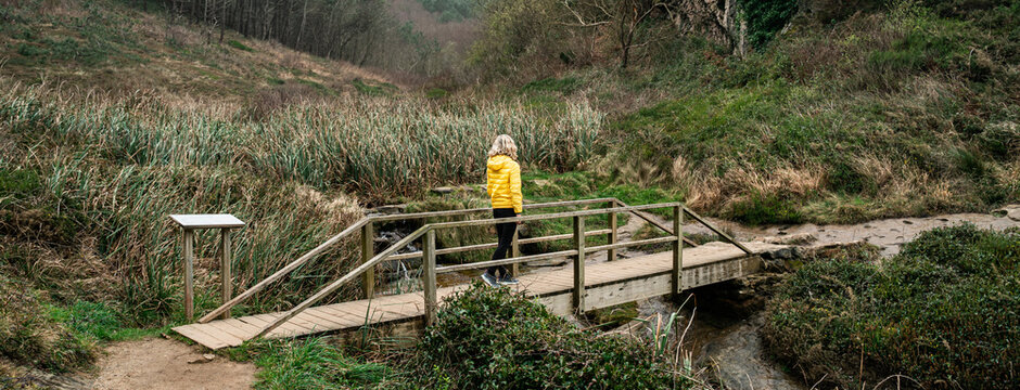 A woman walks across a wooden bridge. Relaxing walk in nature