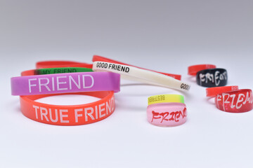 Close up shot of friendship wrist bands and friendship rings on white background