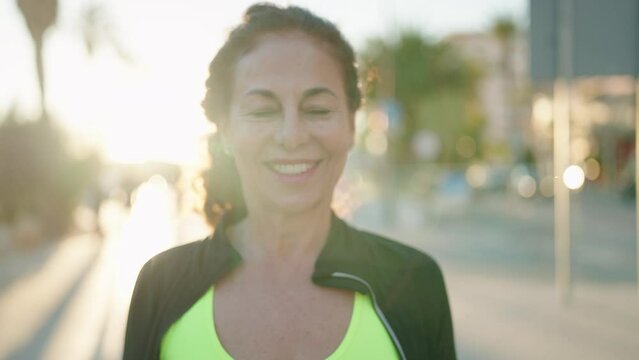 Middle age woman wearing sportswear smiling confident standing at street