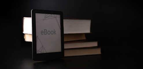 E reader. Digital e book, library reader tablet with books on dark background. Online education course, E learning class and ebook digital technology concept.