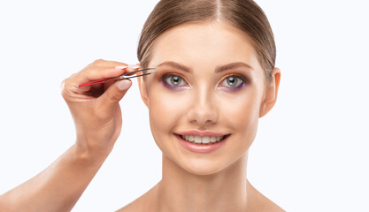 Makeup artist combs eyebrows in a beauty salon. Professional make-up and cosmetic skin care.