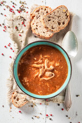 Homemade and spicy tripe soup served with bread and pepper.