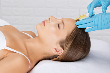 Cosmetologist does prp therapy of a beautiful woman in a beauty salon. Cosmetology concept.