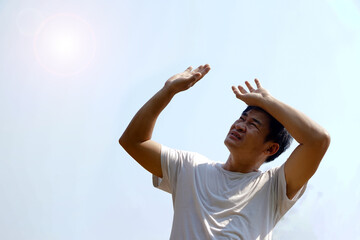 Asian middle-aged man feels hot, stands outdoor in sunny day. Concept : hot weather in summer, high...