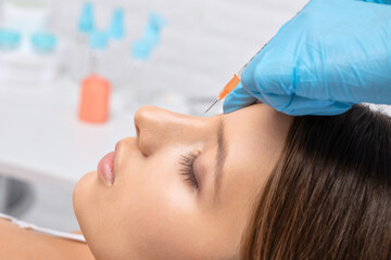 Cosmetologist makes rejuvenating anti wrinkle injections on the face of a beautiful woman. Female...