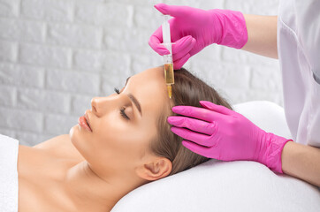 Obraz na płótnie Canvas Cosmetologist makes rejuvenating anti wrinkle injections on the face of a beautiful woman. Female aesthetic cosmetology in a beauty salon.