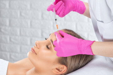 Naklejka premium Cosmetologist makes rejuvenating anti wrinkle injections on the face of a beautiful woman. Female aesthetic cosmetology in a beauty salon.