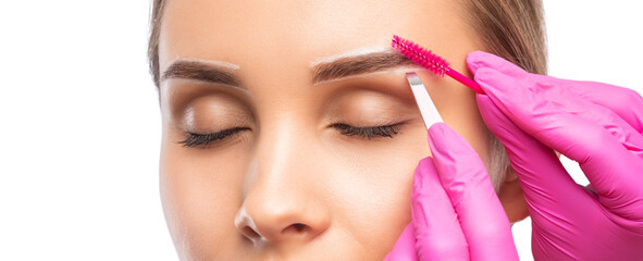 Makeup artist combs and plucks  eyebrows in a beauty salon. Professional make-up and cosmetic skin...