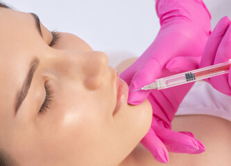 Cosmetologist does injections for lips augmentation and anti wrinkle in the nasolabial folds of a...