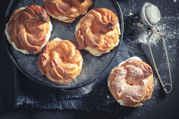 Homemade and delicious cream puffs and strainer with powdered sugar