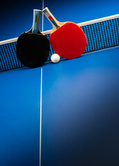 Ping pong rackets and balls on a blue table with net.