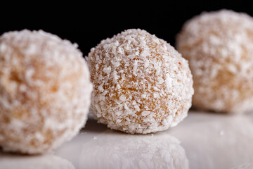 Beautiful sweets with coconut on a white plate on a black background
