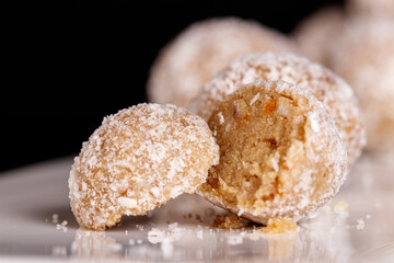 Beautiful sweets with coconut on a white plate on a black background