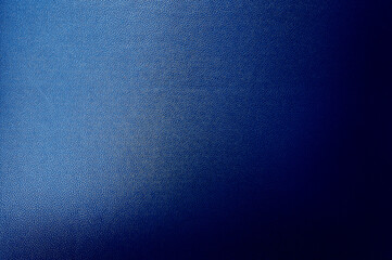 luxury dark blue leather texture background showing grain and a shaft of light across. gradient blue artificial leatherette texture use as background, close up view, with blank space for design.