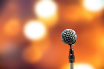 Microphone Public speaking background, Close up microphone on stand for speaker speech presentation stage performance with blur and bokeh light background.