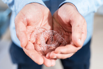 The orthodontist doctor holds transparent aligners in his hands