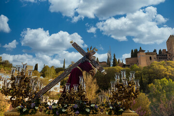 Procession of holy week in granada next to the alhambra. Place of vacations to enjoy the tourism in spain in vacations. Jesus carrying the cross. - obrazy, fototapety, plakaty