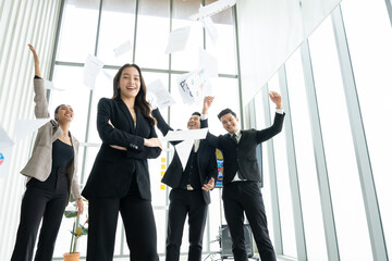 Overjoyed young asian businesspeople throw paper up in air feel excited about successful startup...