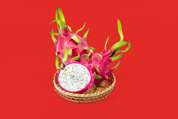 Dragon fruit slice in bamboo basket isolated on red background with clipping path.
