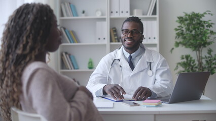 Smiling doctor obstetrician conducting health check-up of pregnant black woman