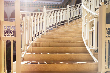 A beautiful staircase with white railings goes up. Steps close-up in the sun