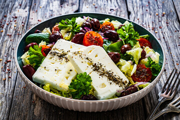 Fresh Greek salad - feta cheese, cherry tomatoes, cucumber and onion on wooden table
