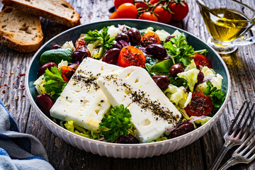 Fresh Greek salad - feta cheese, cherry tomatoes, cucumber and onion on wooden table
