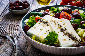 Fresh Greek salad - feta cheese, cherry tomatoes, cucumber and onion on wooden table
