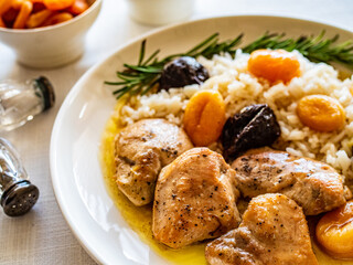 Chicken nuggets with rice, plums and apricots on white table
