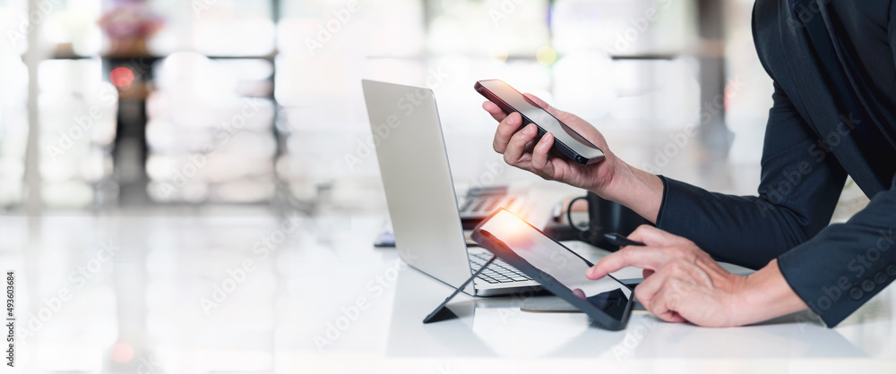 Poster man using smart phone, digital tablet and laptop computer at office.