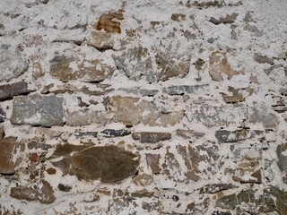 Close up of old barn facade. Stone wall with crumbling white plaster.