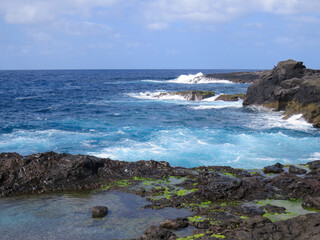 Pescador en las rocas de la localidad de El Puertillo, Gran Canaria, España. Paisaje agreste modelado por las olas sobre las rocas volcánicas.